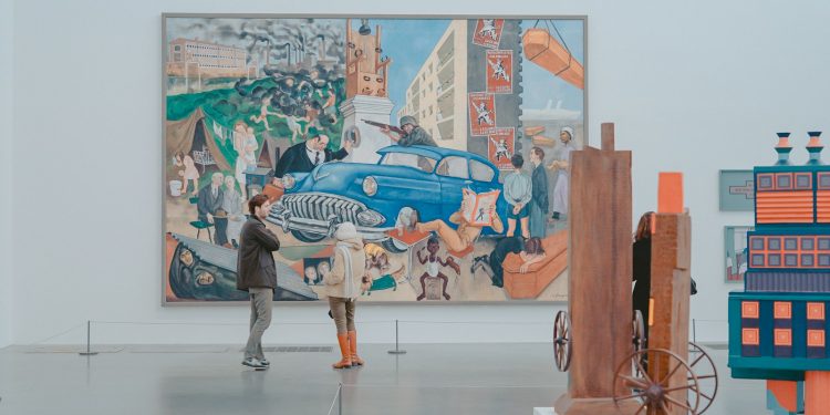 man and woman standing in front of painting in gallery