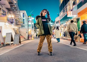 woman in green jacket stands and pose on street